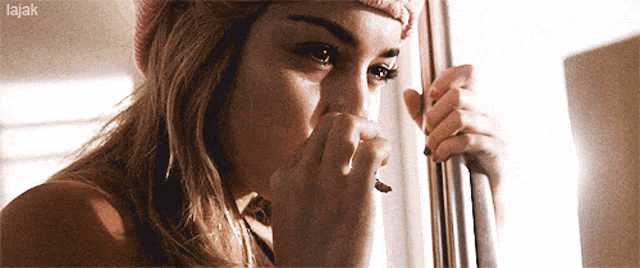a woman in a pink hat looks out of a window with the word lajak on the bottom