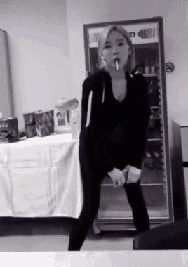 a black and white photo of a woman standing in front of a fridge