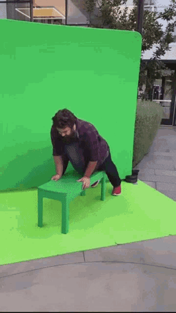 a man is sitting on a green table in front of a green wall
