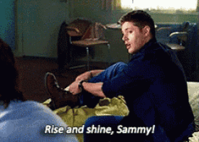 a man sits on a bed with his legs crossed and says rise and shine sammy !