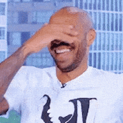 a man is covering his face with his hand while laughing .
