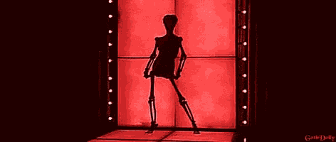a skeleton is standing in front of a red wall and the words gothic dolby are on the bottom right
