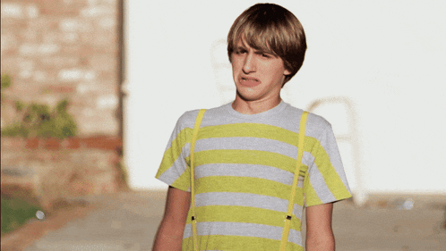 a young man wearing a yellow and grey striped shirt and suspenders