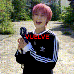 a young man with pink hair is holding a fan and the word vuelve is on the bottom