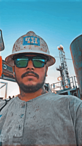 a man wearing a hard hat and sunglasses has the letter h on his hat
