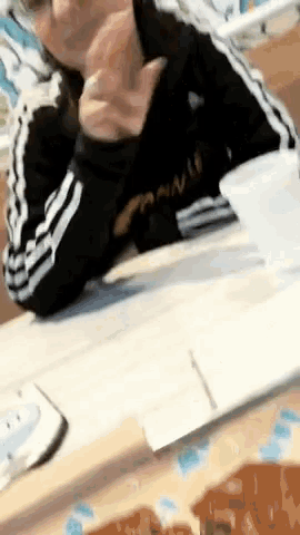 a person is sitting at a table with a cup of coffee and a piece of paper on it