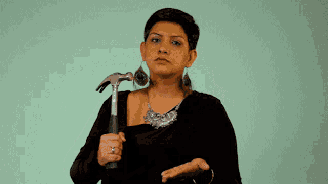 a woman in a black dress holds a hammer in her hand