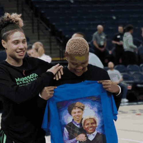 a woman wearing a minnesota basketball shirt holds a blue t-shirt