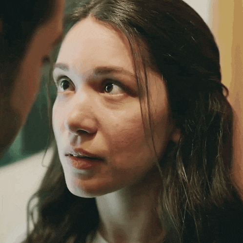 a close up of a woman 's face with a man behind her