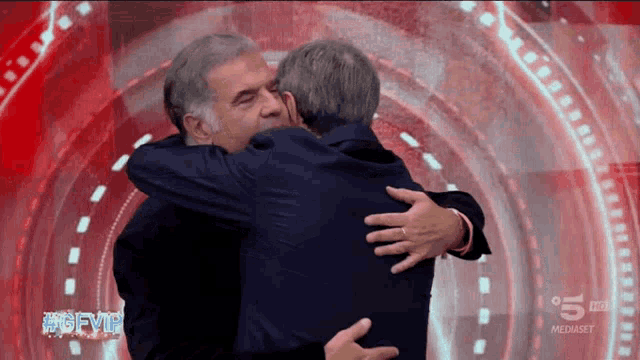 two men hugging each other in front of a screen that says 5