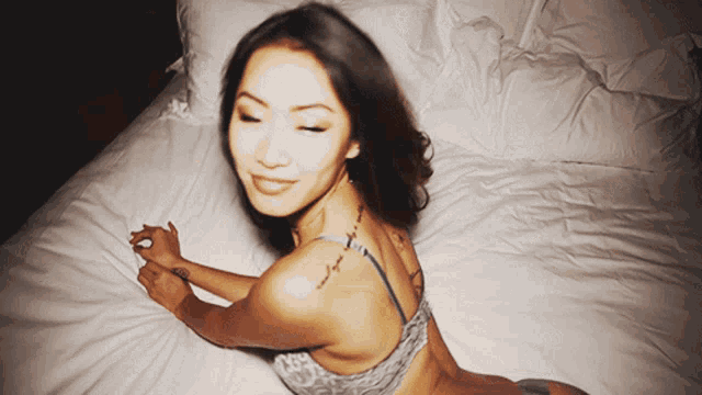 a woman with a tattoo on her back is laying on a bed with her eyes closed