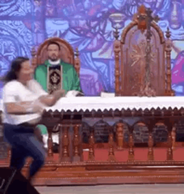 a woman is dancing in front of an altar in a church while a priest sits behind her .