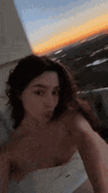 a woman is taking a selfie in front of a sunset .