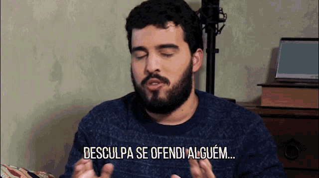 a man with a beard and a blue sweater says desculpa se ofendi alguem