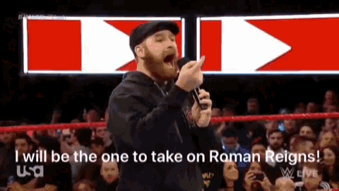 a man is holding a microphone and saying " i will be the one to take on roman reigns " in front of a crowd