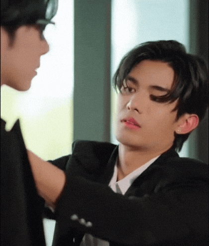 a man in a suit and tie is touching the arm of another man in a suit .