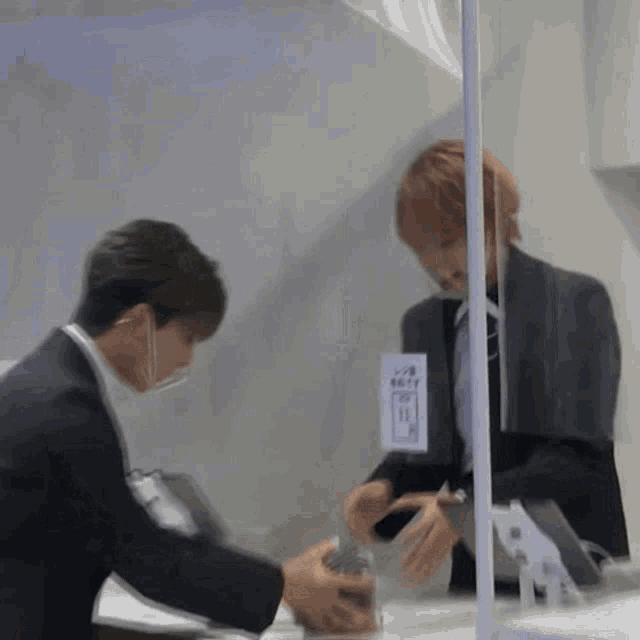 a man in a suit is standing in front of a glass wall with a sign that says ' a ' on it