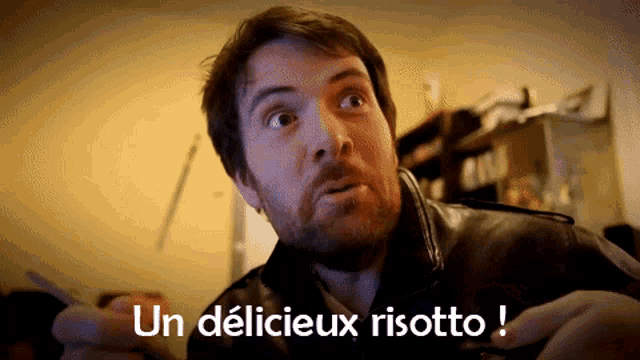 a man with a beard is holding a plate of food and says un deliceux risotto