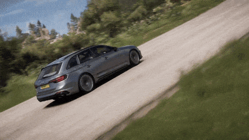 a silver audi is driving down a dirt road with trees in the background