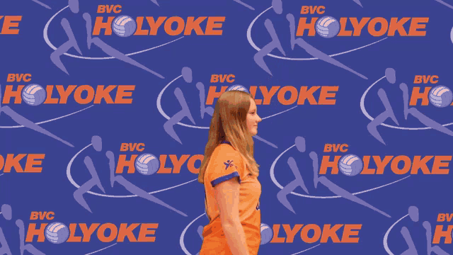 a woman in an orange jersey with the number 61 throws a ball