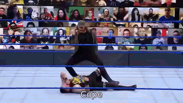 a man is standing on top of a woman in a wrestling ring while a crowd watches .