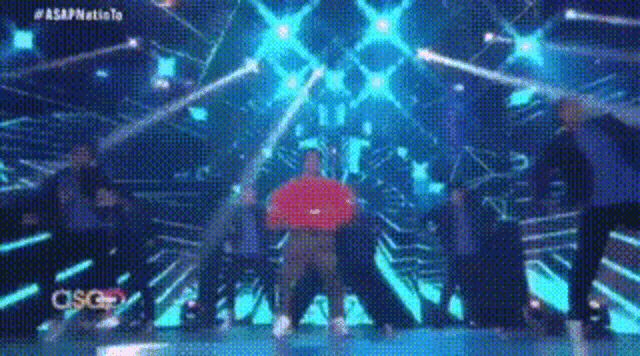 a group of people are dancing on a stage with a lot of lights .