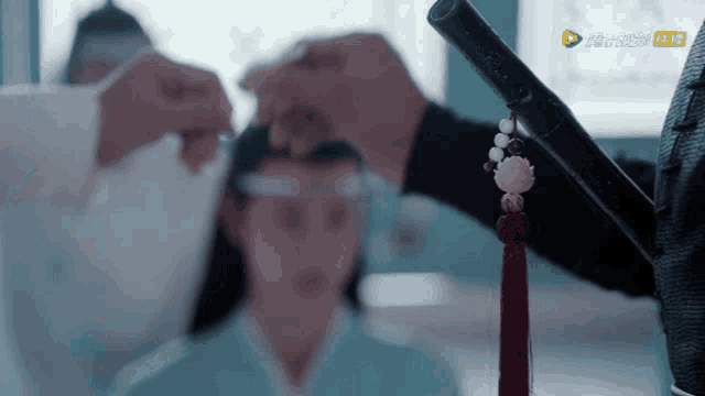 a man is holding a sword in front of a woman 's head in a room .