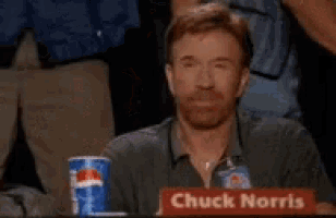 chuck norris is sitting at a table with a pepsi cup
