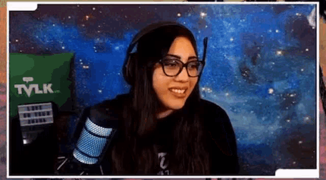 a woman wearing glasses and headphones is sitting in front of a microphone and smiling .