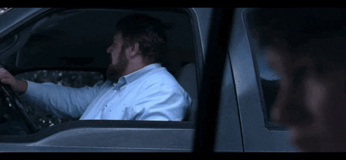 a young boy is sitting in the back seat of a red car