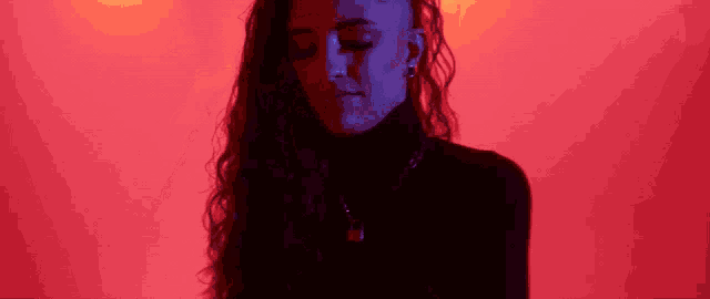 a woman is standing in front of a red wall with her eyes closed .