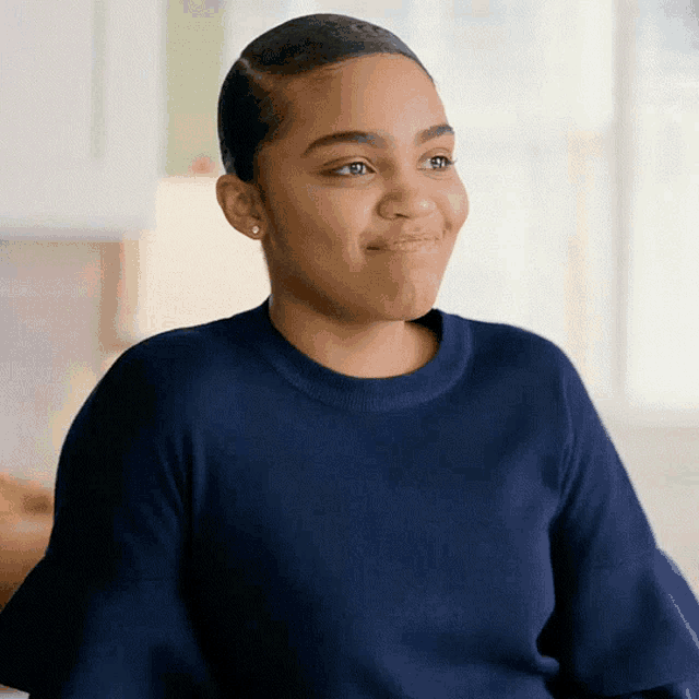 a young girl in a blue sweater is smiling