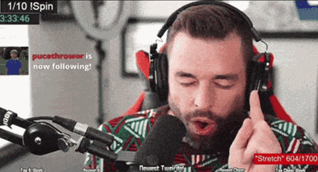 a man wearing headphones is talking into a microphone with 1/10 ispin displayed on the screen behind him