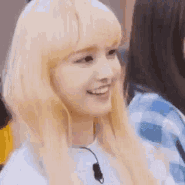 a close up of a woman with blonde hair wearing a white shirt and smiling .