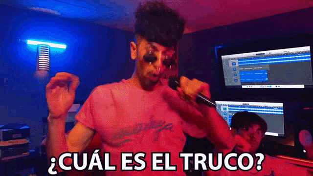 a man singing into a microphone with the words " cual es el truco " written below him