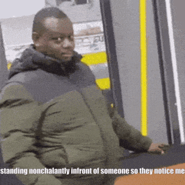 a man in a green jacket is standing nonchalantly in front of someone so they notice me