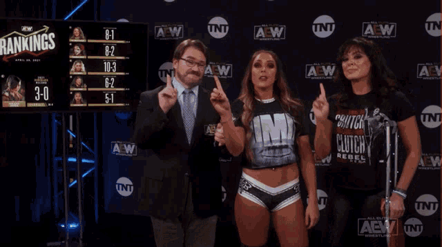 a man and two women are standing in front of a wall that says aew on it