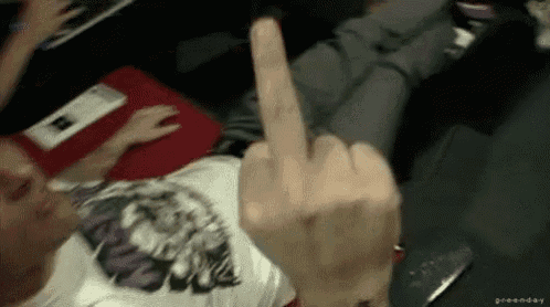 a man is laying on a couch giving the middle finger .