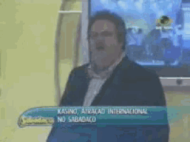 a man in a suit stands in front of a tv screen that says casino atracao internacional no sabadaco