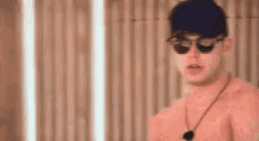 a shirtless man wearing sunglasses and a baseball cap .