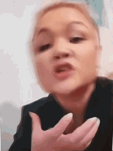 a woman is making a funny face with her hands in front of her mouth .