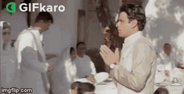 a man in a white suit is standing in front of a group of people .