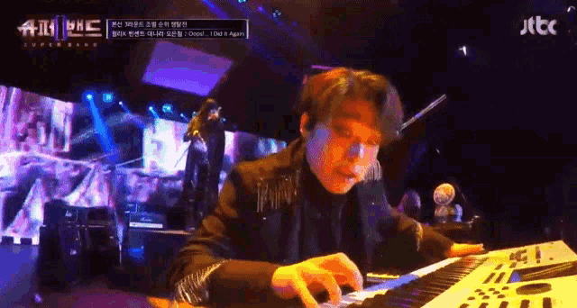a man is playing a piano in front of a screen that says jtcc