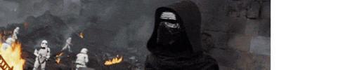 a man in a black hooded cape stands in front of a fire