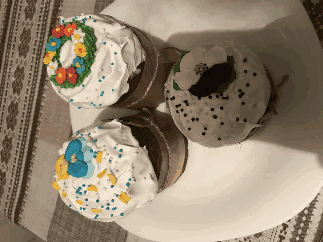 three cupcakes with white frosting and sprinkles are on a plate