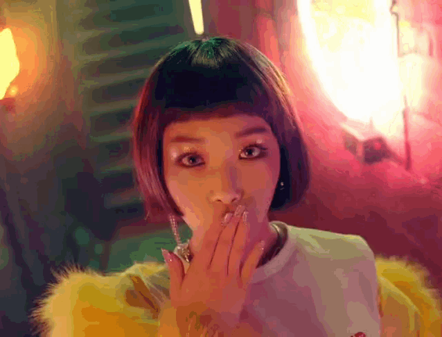 a woman covering her mouth with her hand in front of a neon sign