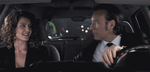 a man and a woman are sitting in a car and the man is wearing a wedding ring
