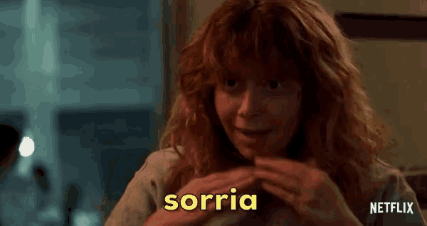 a woman with red hair is smiling and waving her hand with the word sorria written in yellow