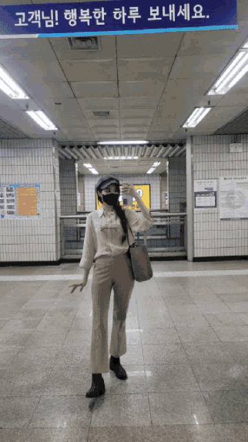 a woman wearing a mask stands in front of a sign that says ' 고래님 ! '