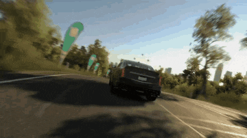 a car is driving down a road with trees and a green flag in the background